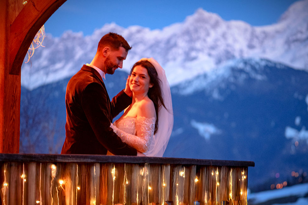 Un couple de jeune mariés au crépuscule sur le balcon d'un chalet en hiver avec le Mont-Blanc en arrière-plan
