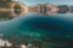 Reflections of Cleetwood Cove on Crater Lake at Crater Lake National Park, Oregon, USA. Crystal clear blue water with visible rocks