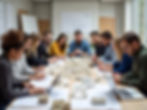 Architectural team collaborating on building models and blueprints in a meeting room.