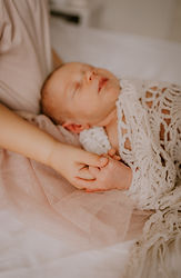 Detail van 2 handjes van een newborn baby en grote zus tijdens een newborn shoot in Mechelen.