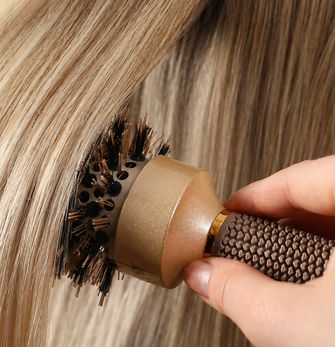 Close-up of brushing smooth blonde hair with a round styling brush.