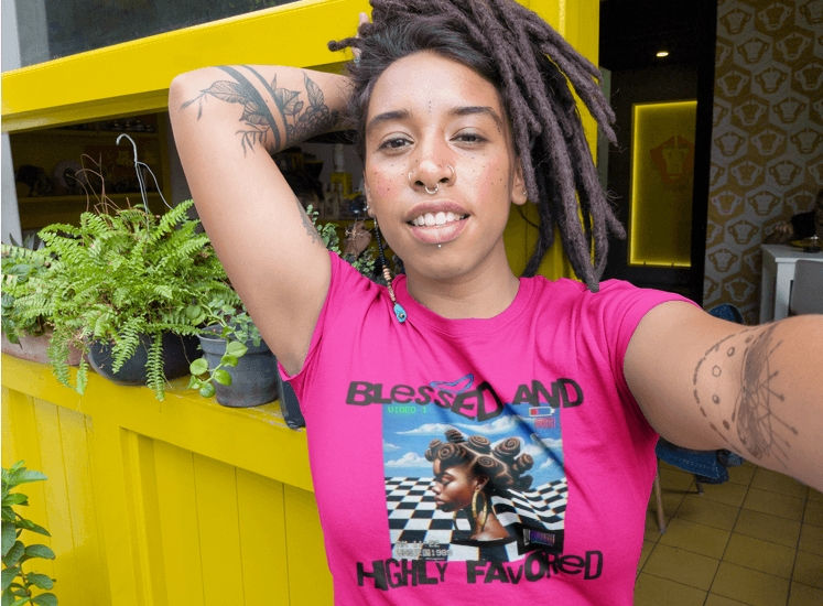 Model wearing a Blessed and Highly Favored Christian graphic tee in a pink shirt with faith inspired streetwear design