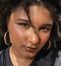 mulher negra maquiada usando brincos e colares dourados