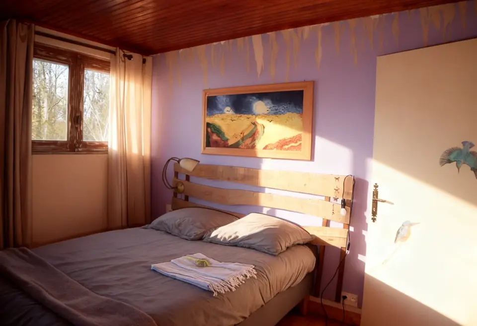 Double bedroom with sun coming in on the bed and painting of a bird on the door