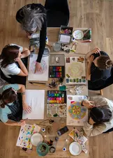 four pregnant woman at table doing art led by an instructor. Creative workshop during the hummingbee pregnancy retreat. top view