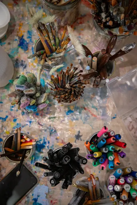 Paint brushes and other art material on a table, set up for a painting workshop at the hummingbee pregnancy retreat