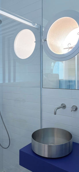 Dettaglio lavabo in acciaio e doccia con rubinetteria cromata nel bagno di design in stile nautico a Praiano.