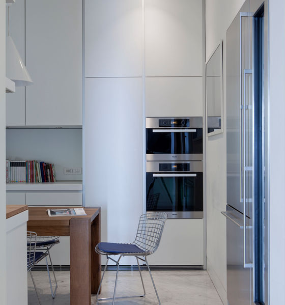 cucina in Corian e legno laccato, Bulthaup. Tavolo Bigfoot di Philipp Mainzer per E15, sedie in acciaio cromato di Harry Bertoia per Knoll. A sospensione lampade Diabolo di Achille Castiglioni per Flos.