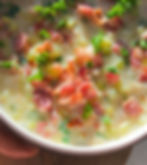 베이컨과 파슬리가 올려진 크리미한 수프가 그릇에 담겨 있음. 따뜻한 분위기의 맛있는 음식.