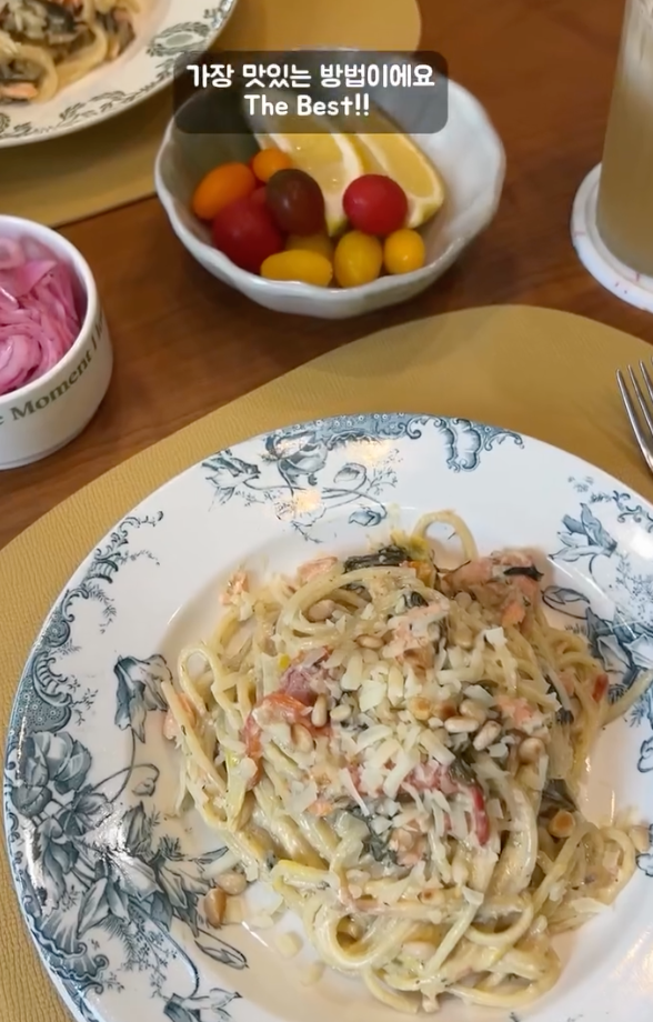 크림 파스타가 담긴 접시가 테이블 위에 놓여 있고, 옆에 과일과 레몬이 담긴 그릇이 있다. 상단에 "가장 맛있는 방법이에요 The Best!!"라는 텍스트가 있다.