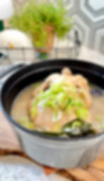 냄비 안에 맛있어보이는 삼계탕이 들어있고, 파가 고명으로 들어있다.