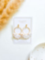 Marbled white and gold polymer clay earrings with textured gold-plated hoop and wing-like drop design.