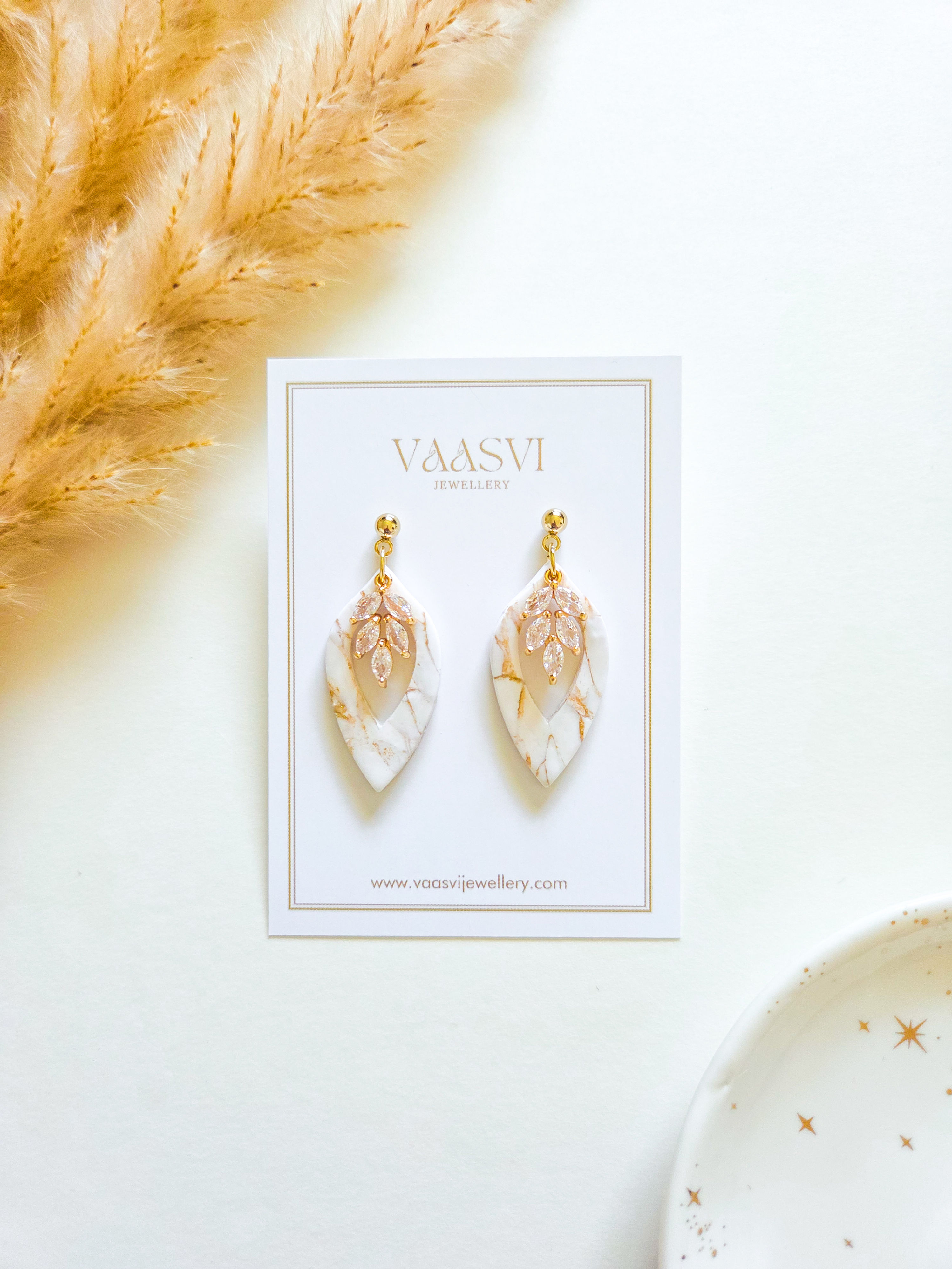 Marbled white and gold leaf-shaped polymer clay earrings with gold and zircon charm.