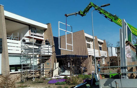 Plaatsing van een groot kunststof kozijn met kraan bij renovatie van een woning