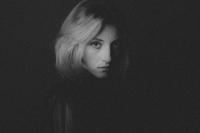 photographie noir et blanc, femme blonde, fond noir, regarde l'appareil photo
