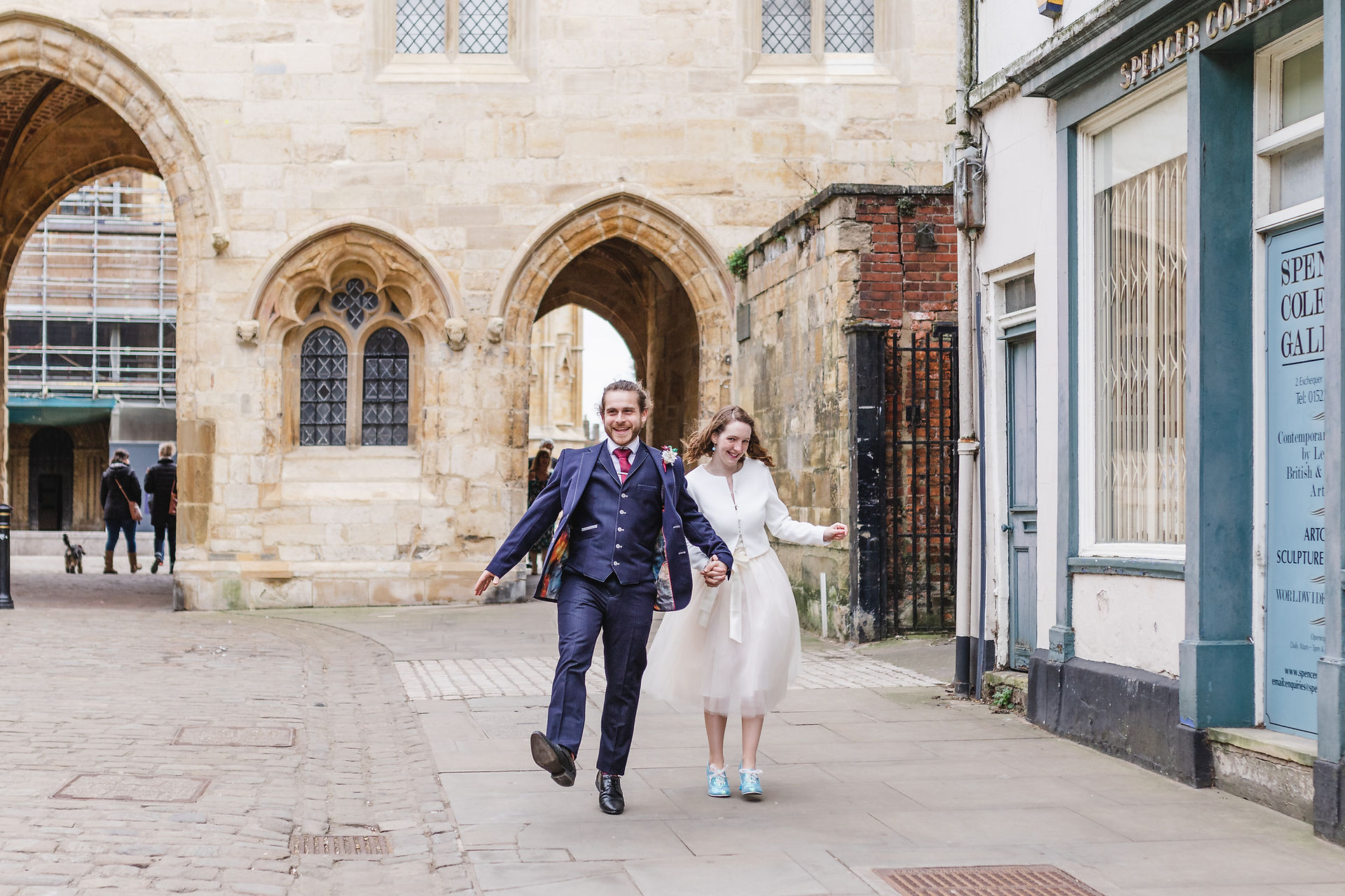 Bride and Groom skipping through the Exchequer Gate for their Lincoln Cathedral Wedding Portraits