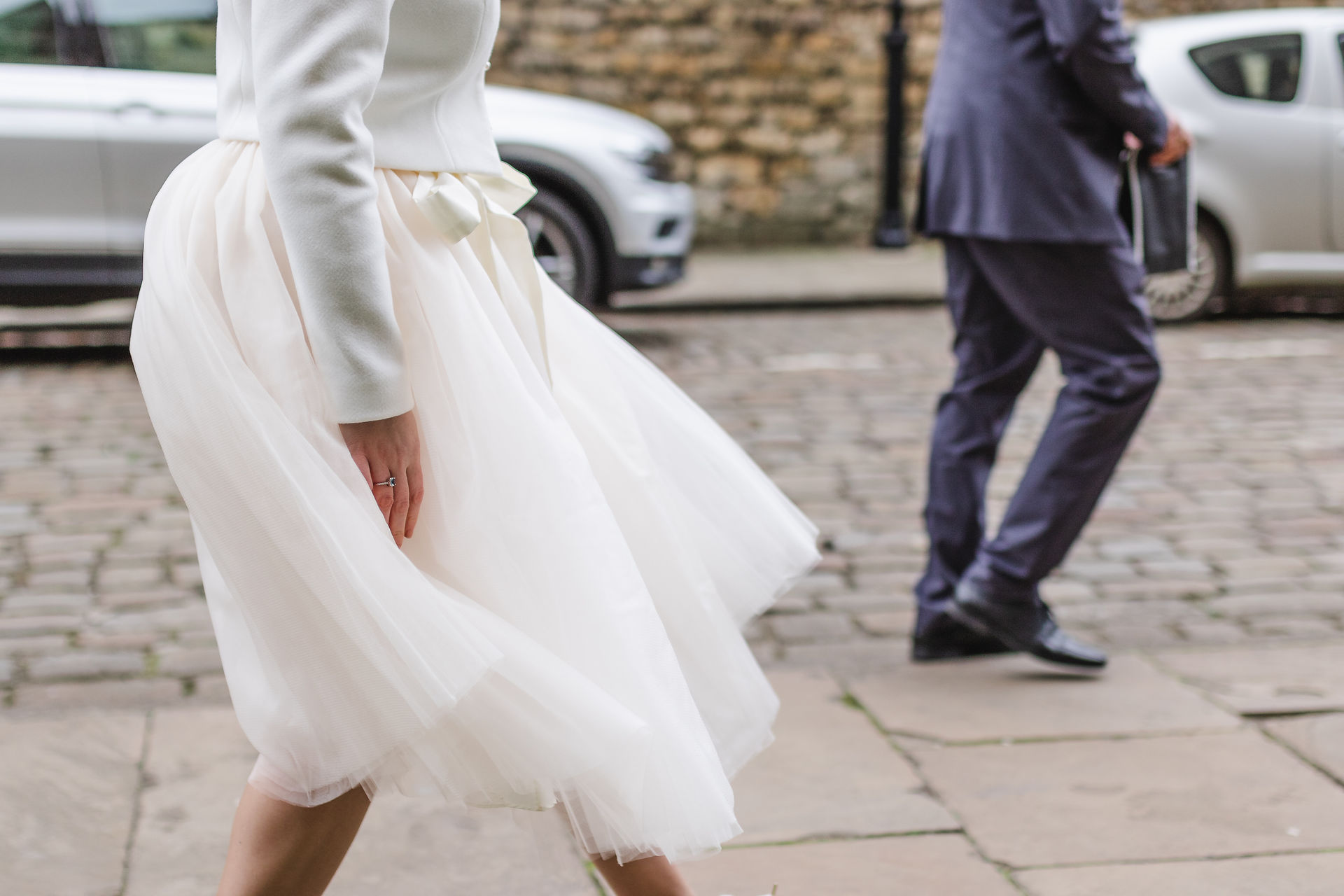 Close of of brides dress as she walks around the grounds of Lincoln Cathedral at Wedding