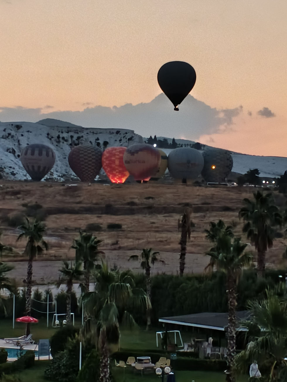 Hot air balloons rising over the travertines at dawn at Pamukkale