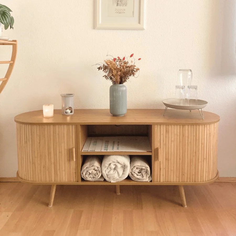 Einblick in die entspannte Atmosphäre der Stressablage in Steyr mit Sideboard aus Naturholz, bunten Trockenblumen, Getränkebar, Kerzenlicht, Coaching- & Massage-Material
