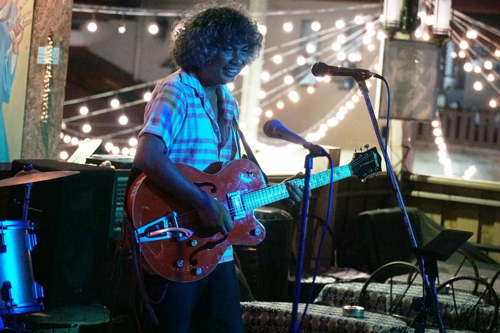 A musician performing live at a cozy outdoor venue in Chiang Mai, surrounded by twinkling lights.