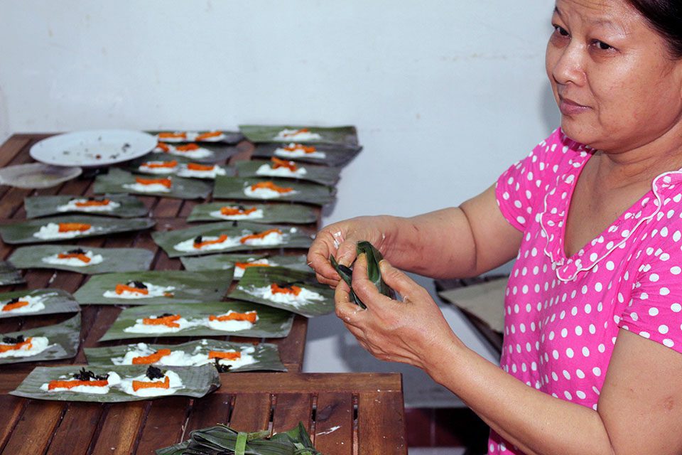 A woman in Vietnam making Banh Bot Loc dumplings wrapped in banana leaves.