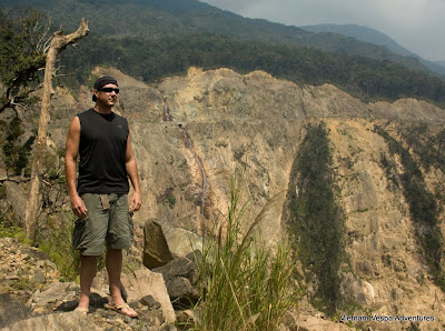 A traveler standing at the edge of a scenic viewpoint, overlooking a deep valley and winding roads in Vietnam.