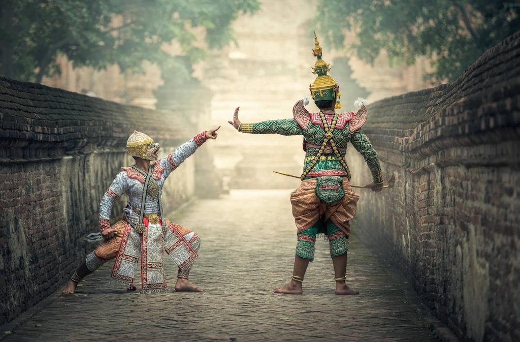 Traditional Thai dancers in full costume performing an ancient dance in a historic alley.