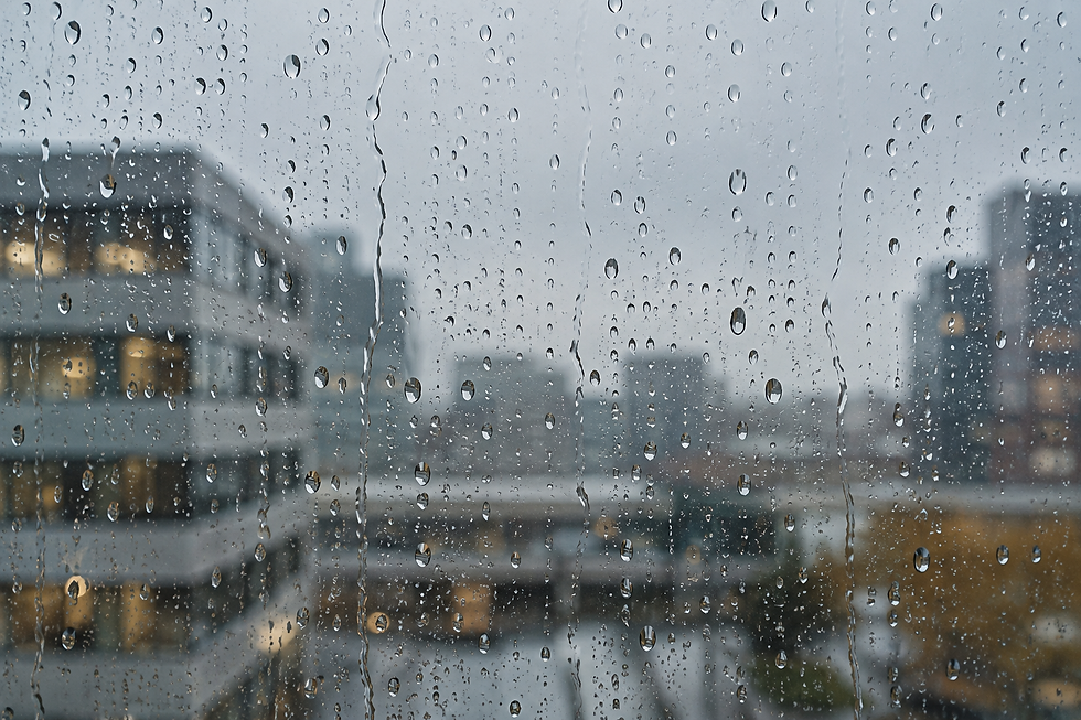Regendruppels op een raam met onscherpe kantoorgebouwen op de achtergrond