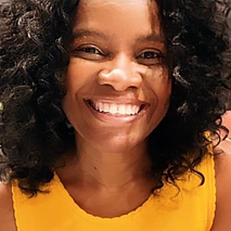 Smiling woman (the coach) with shoulder length curly hair and yellow dress