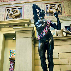 A view of the interior of Manchester Art Gallery, where one of the statues is wearing a sash.