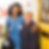 Smiling nurse in blue uniform with clipboard hugs elderly woman in polka dot shirt at yellow door. Bright, positive mood.