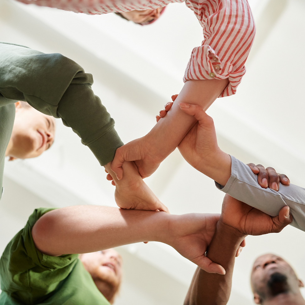 A diverse group of people form a supportive circle by holding wrists, set against a bright white background, symbolizing unity and teamwork.