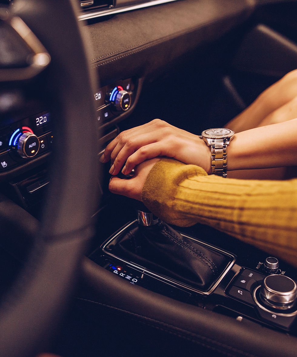A male and a female hands one on top of the other on top of a stick shift in a car