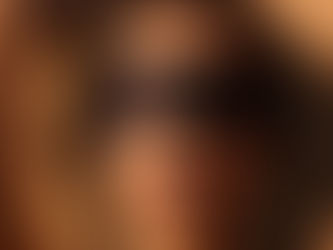 A close-up, artistic portrait of a woman's face in soft, golden light. She wears a smooth black silk blindfold that covers her eyes, her lips slightly parted in serene vulnerability. Her expression is calm, exuding confidence, submission, and quiet desire. The lighting is warm and moody, casting gentle shadows across her features. Strands of hair softly frame her face, and the blurred hint of her arms stretched above her head creates a sense of openness and intimacy. The mood is cinematic, sensual, and reverent.