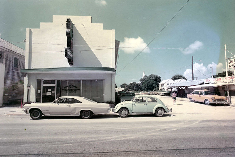 Two cars in front of a building with an awning and a marquee sign.