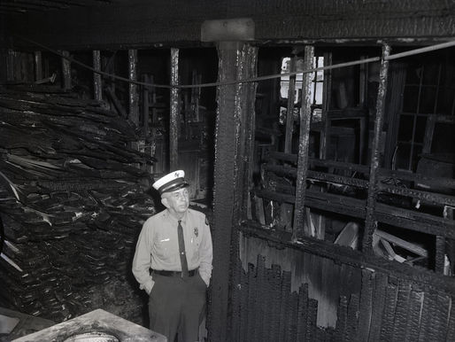 A man in a fire department uniform inside a burned out structure