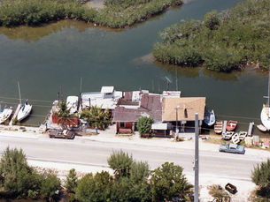 Aerial view of boats and buildings along a waterfrotn road