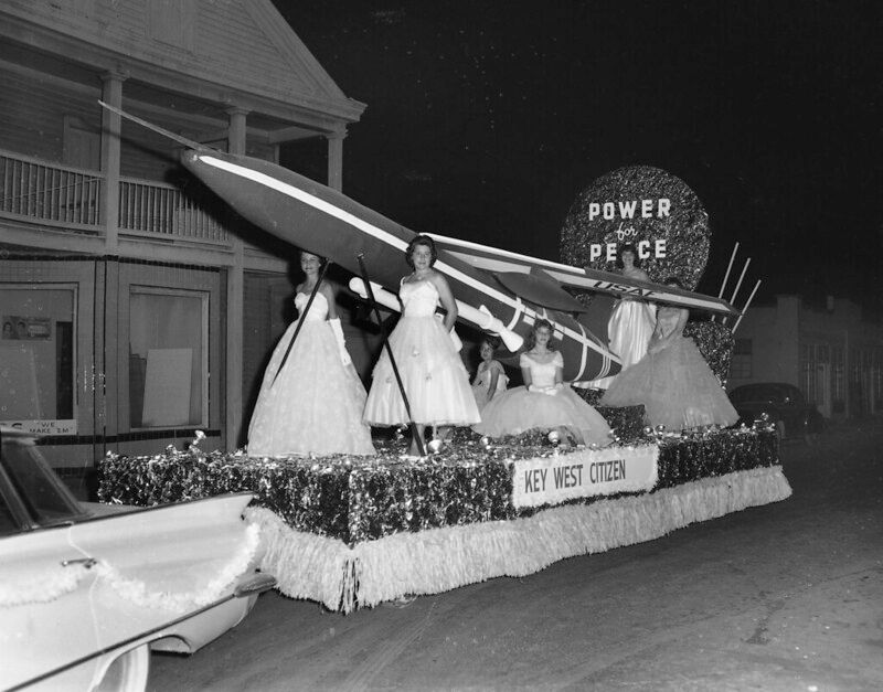 Women wearing ball gowns on a float with a missile and signs reading Power for Peace and Key West Citizen.