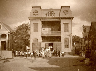 A group of people in front of a three-story building.