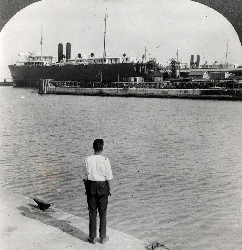 A person looks cross water at a ferry tied up at a pier.
