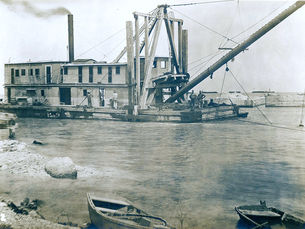 a marine dredge working with a shoreline in the foreground