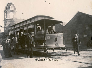 A streetcar with people on and around it. Writing on the photo reads streetcar and 1904.