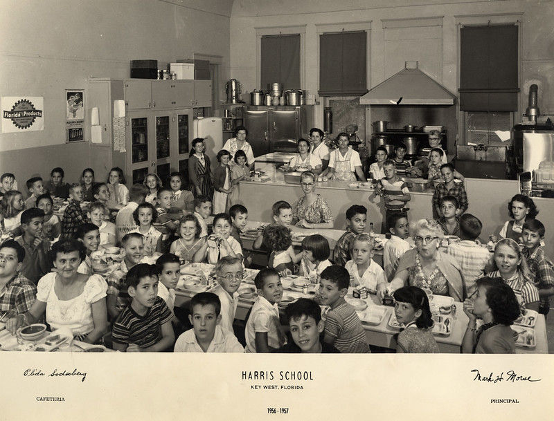 Children and some adults in a cafeteria.