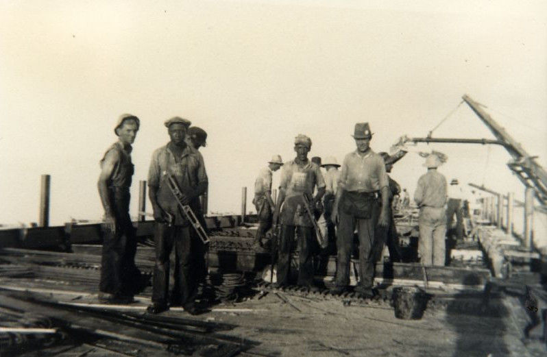 A group of men standing on a bridge under construction.