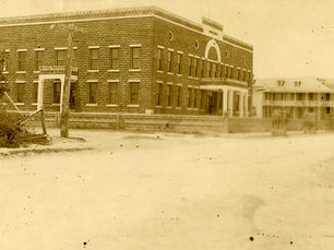 two large buildings on a dirt road