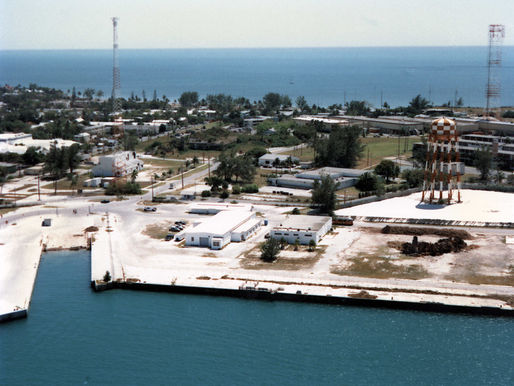 A waterfront area with a seawall, buildings and metal towers