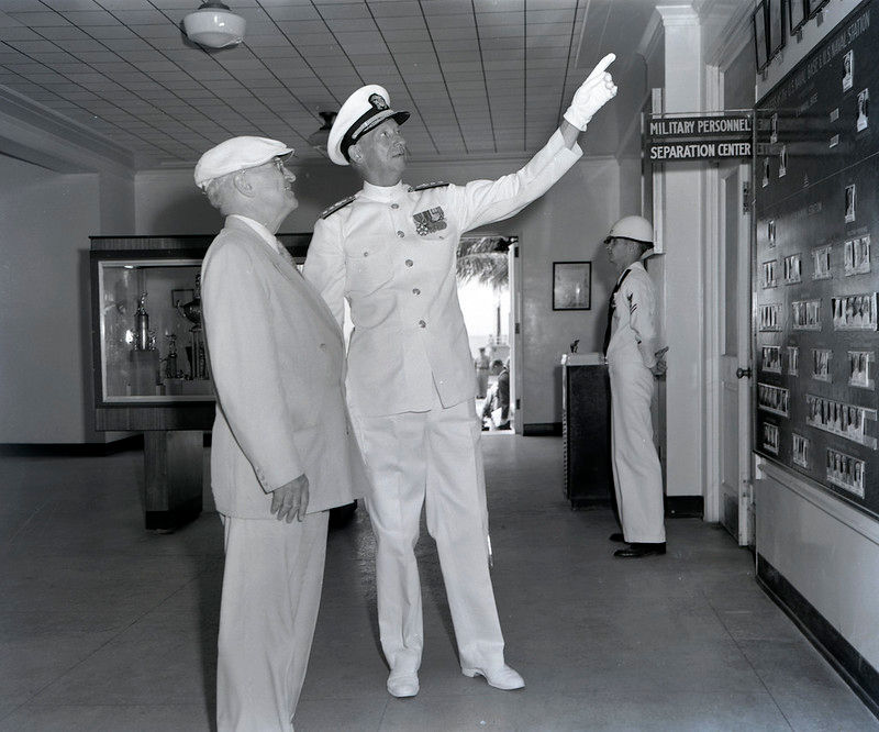 Two men, one in a Navy officer's uniform, looking at a display.