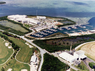 Aerial view of a shoreline with a marina and a large building in the background