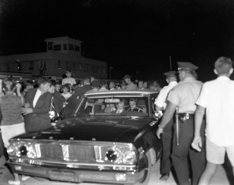 A police car with a big crowd around it.