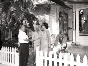 A man and woman shake hands, while another man looks on.